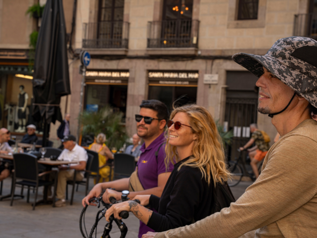 Group members smiling while listening on their e-bikes next to the Council of Barcelona.